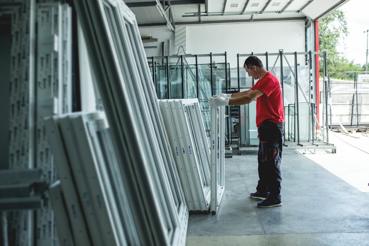 Craftsman working on window and door profiles in a factory setting