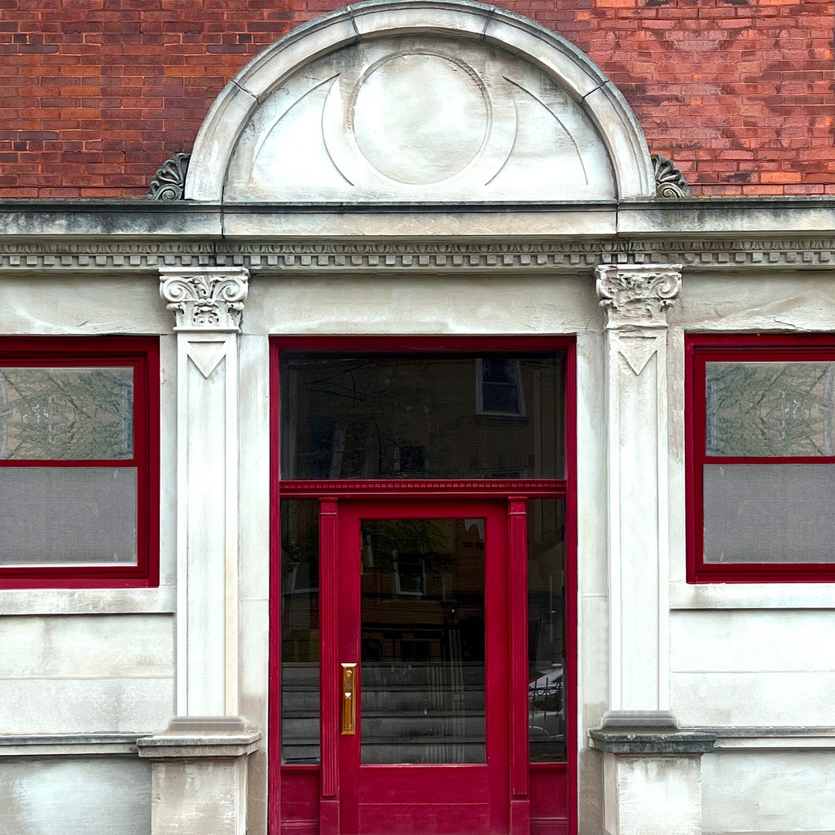 Ornate arched entrance with white stone columns on a historic brick residence